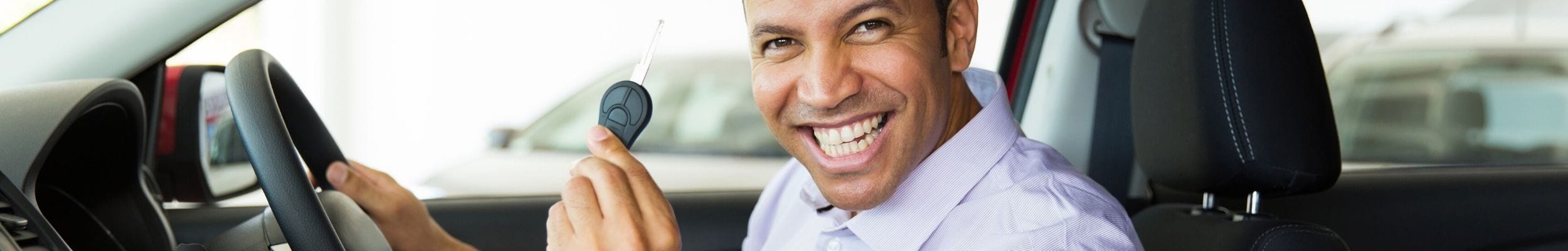 Man smiling in new car with keys