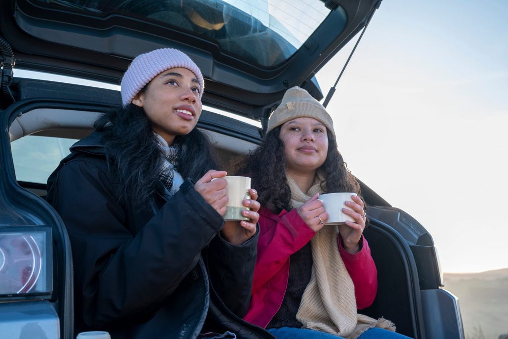 Image of friends sat in the boot of a car drinking from mugs